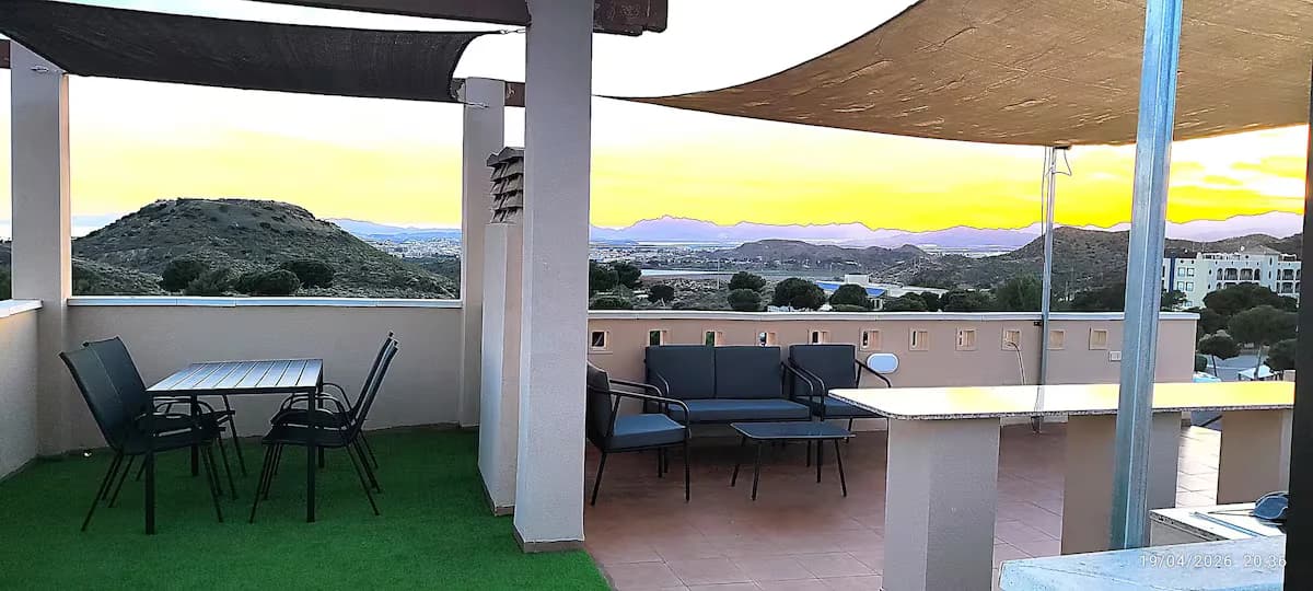Solárium privado con zona de comedor y sofás al atardecer