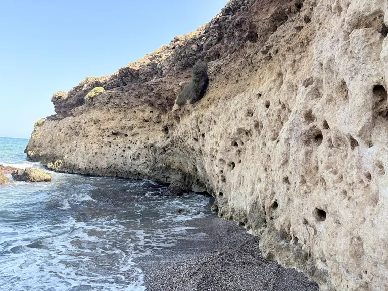 Un bloque de roca clara erosionada al borde del agua en Playa Larga, con el mar turquesa rompiendo a sus pies