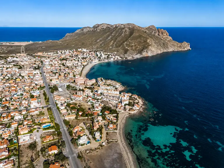 El cabo Cope entrando en el mar, con el caserío y la playa a sus pies y el agua turquesa de la cala