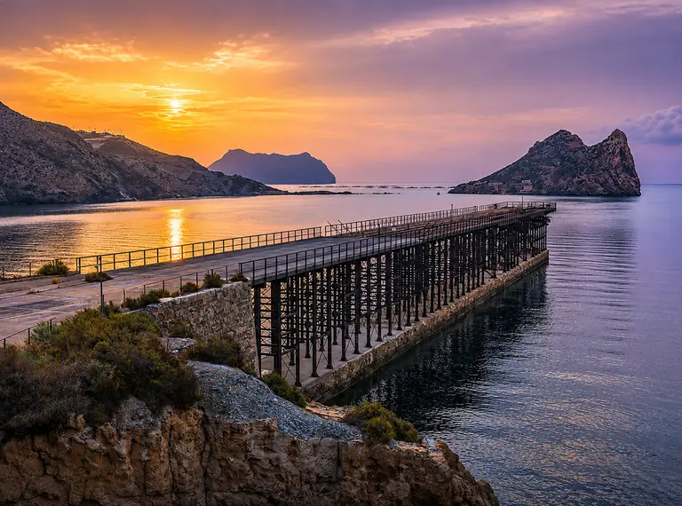 El embarcadero del Hornillo al atardecer, con el sol poniéndose sobre el mar y la isla del Fraile recortada al fondo