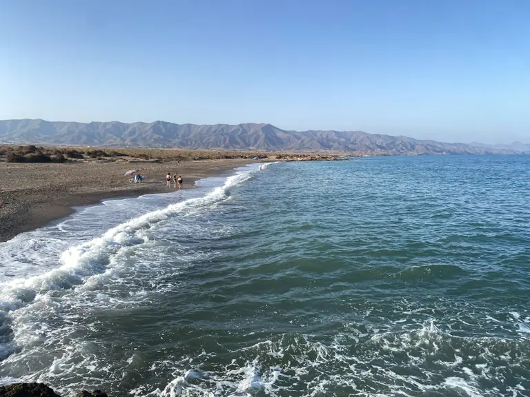 La costa de Marina de Cope: una playa larga de grava, la línea de espuma y la Sierra de la Almenara detrás