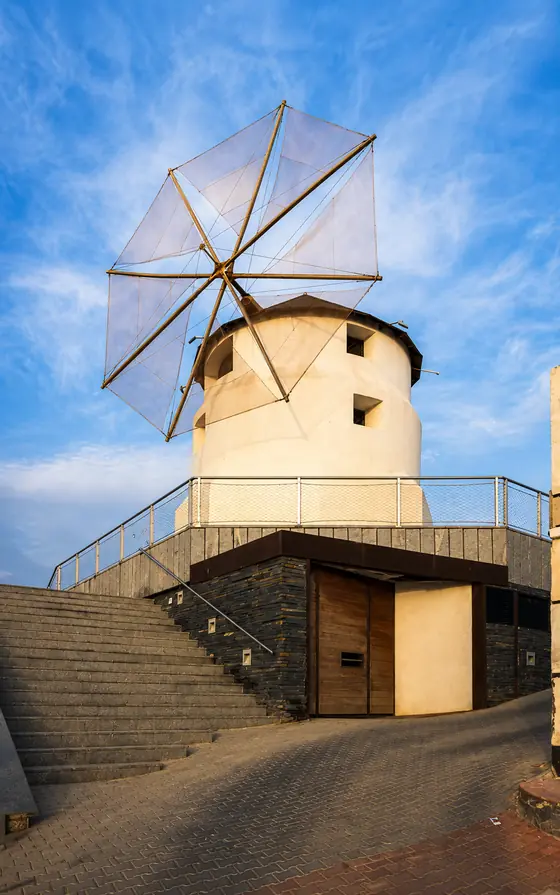 Un molino de viento encalado con las aspas montadas, al final de una escalera de piedra