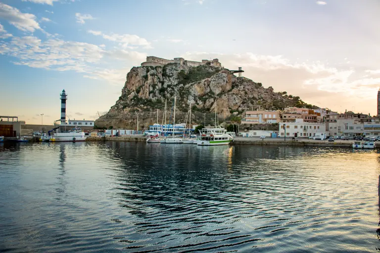 El puerto de Águilas al atardecer, con los barcos amarrados y el castillo de San Juan sobre la roca