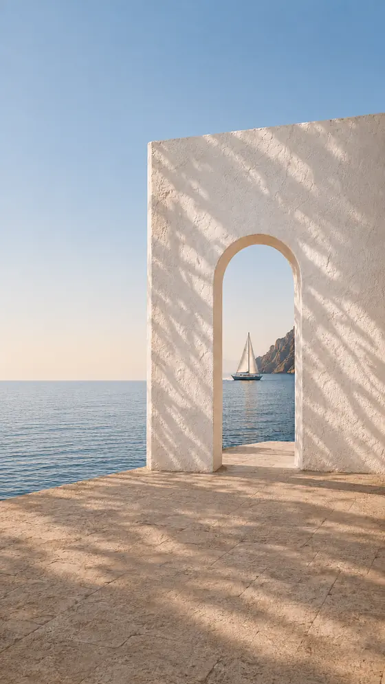 Arco de piedra encalada abierto al Mediterráneo, con un velero navegando al fondo
